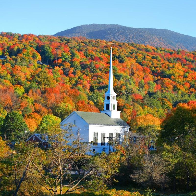The white steeple of Stowe's church against a hillside of peak autumn color, Mount Mansfield country